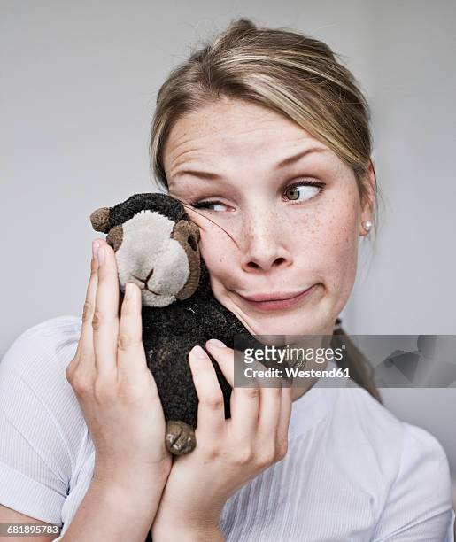 young woman making a funny face holding cuddly toy - jeune d'esprit photos et images de collection
