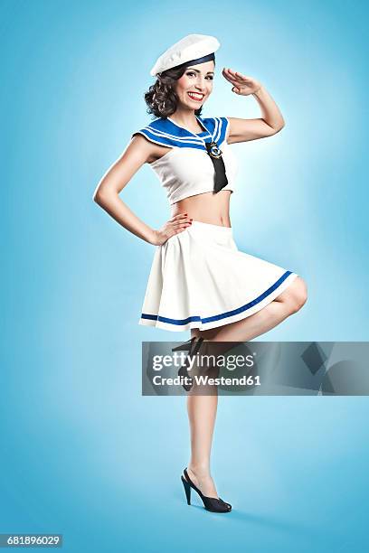 woman wearing sailor suit in pin-up style saluting - pin-up meisje stockfoto's en -beelden