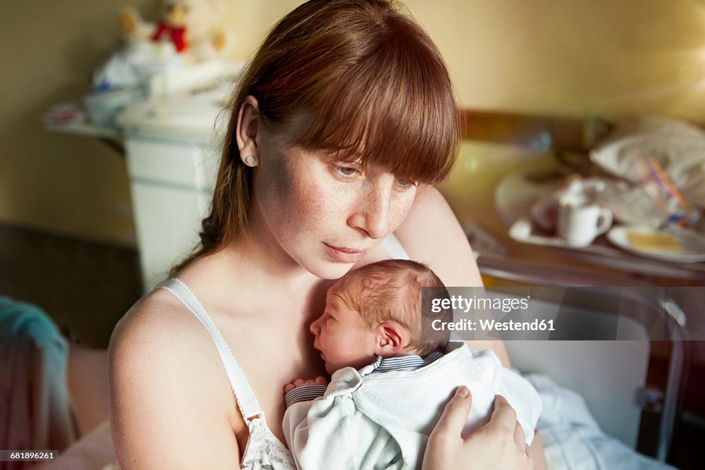 Mother holding her newborn baby in hospital room