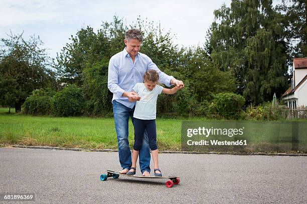 father and daughter longboarding in garden - father longboard stock pictures, royalty-free photos & images