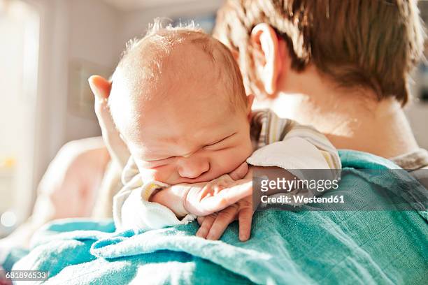 close-up of father holding his newborn son over the shoulder - man touching shoulder stockfoto's en -beelden