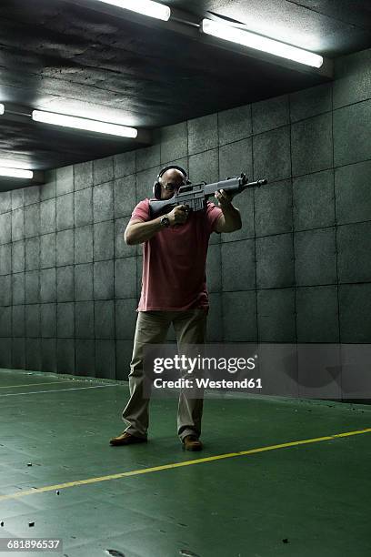 man aiming with a tactical weapon in an indoor shooting range - target shooting stock pictures, royalty-free photos & images
