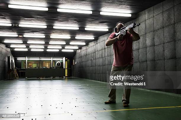 man aiming with a tactical weapon in an indoor shooting range - leuchtgeschoss stock-fotos und bilder