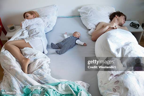 parents sleeping with newborn baby in bed - adult baby women stock pictures, royalty-free photos & images