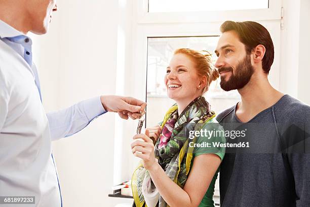 young couple receiving house key from real estate agent - houses for rent stock-fotos und bilder