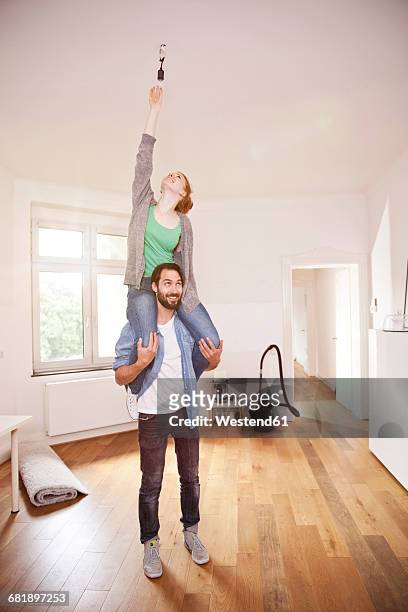 young couple exchanging a light bulb in their new apartment together - carrying on shoulders stock pictures, royalty-free photos & images