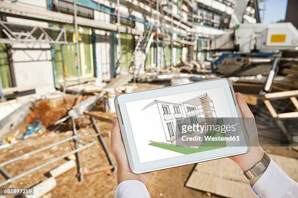 hands holding a digital tablet with an architectural house sketch in front of a contruction site - architekturmodell stock-fotos und bilder