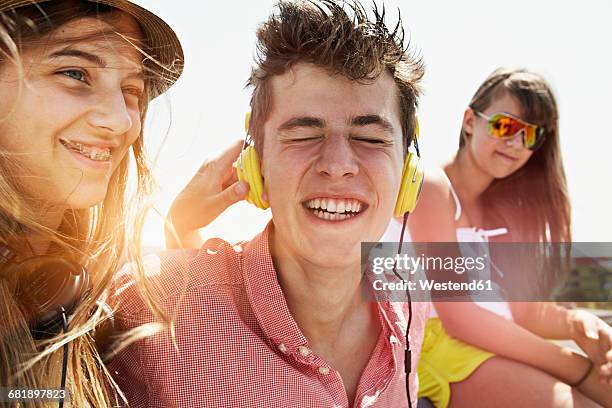 three happy teenage friends with headphones outdoors - girls stock-fotos und bilder