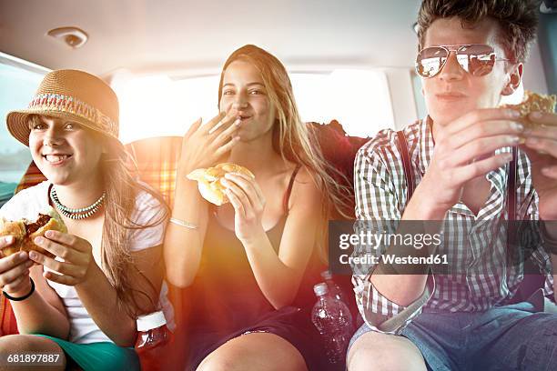 three teenage friends having a snack in car - friends inside car imagens e fotografias de stock