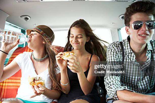 three teenage friends having a snack in car - boy with car stock-fotos und bilder