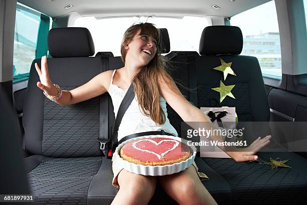 happy girl n car with heart-shaped cake - passagerarsäte bildbanksfoton och bilder