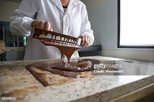 woman tempering melted chocolate on a marble surface - sweet shop stock pictures, royalty-free photos & images