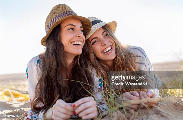 portrait of two best friends with summer hats lying on the beach - girl with beautiful hair stock pictures, royalty-free photos & images