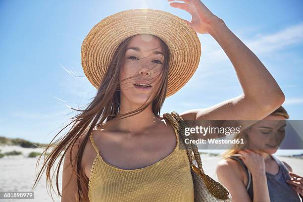 two female friends on the beach - sonnenhut stock-fotos und bilder