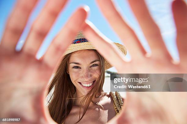 portrait of smiling young woman on the beach - dedos fazendo moldura - fotografias e filmes do acervo