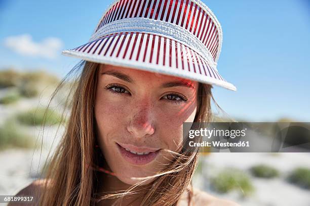 portrait of smiling young woman wearing sun visor on the beach - visor stock pictures, royalty-free photos & images
