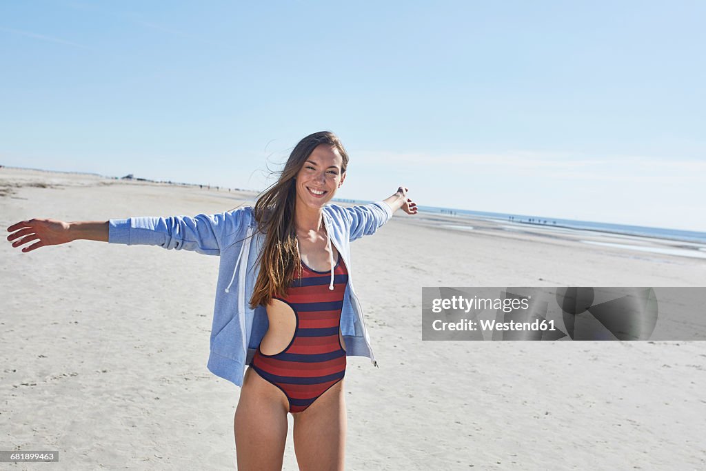 Happy young woman with outstretched arms on the beach