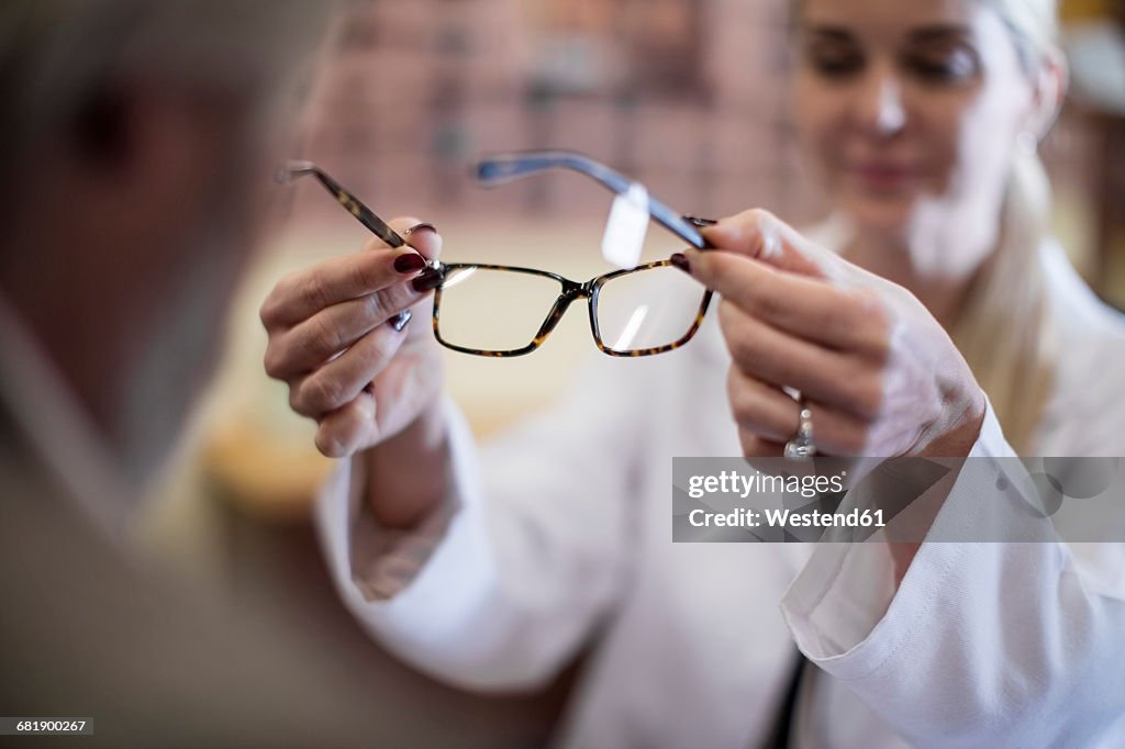 Optician helping customer to choose new spectacles