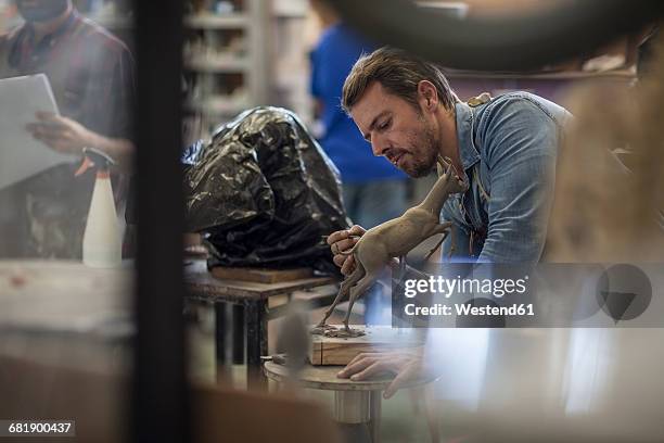 sculptor working in studio on animal figurine - sculpteur photos et images de collection