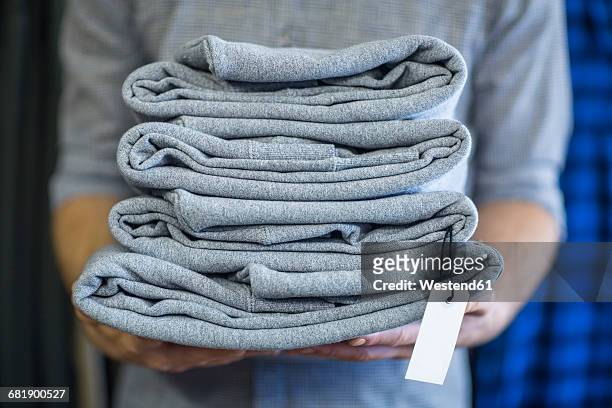 man holding stack of folded clothes - folded clothes stock-fotos und bilder