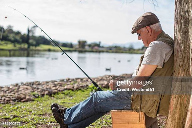 senior man fishing, relaxing at a tree - man sleeping with cap stock pictures, royalty-free photos & images