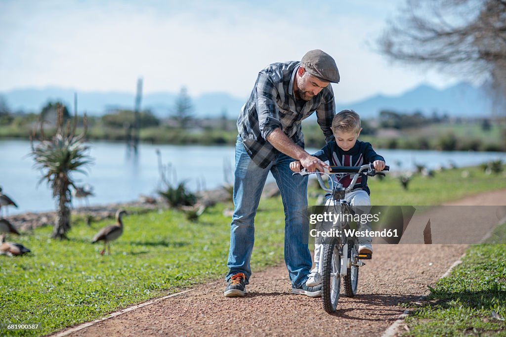Father supporting son on bike