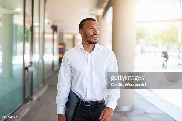 smiling businessman with file - white/black shirt stock-fotos und bilder