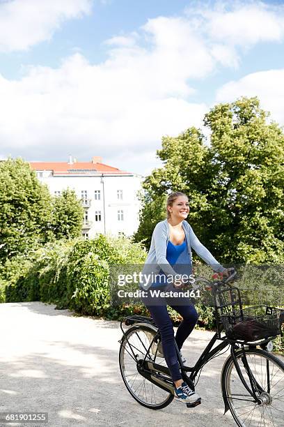 young woman riding bicycle in park - velofahren stock-fotos und bilder