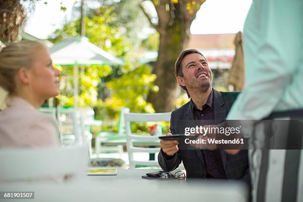 customer handing over bill to waiter at outdoor restaraunt - restaurant bill ストックフォトと画像
