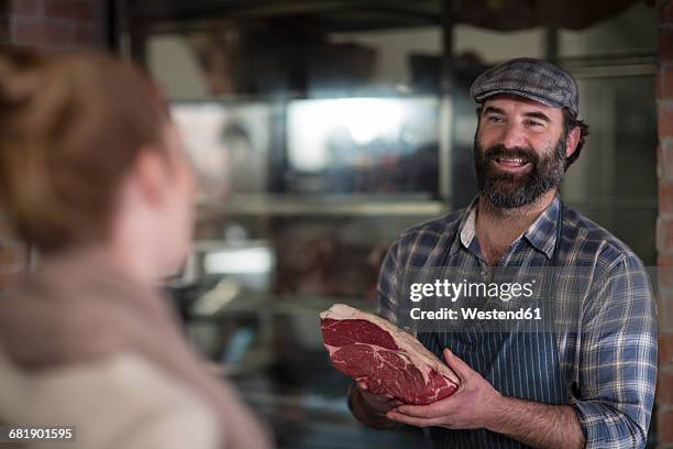 butcher showing meat to woman in butchery - butchery stock-fotos und bilder