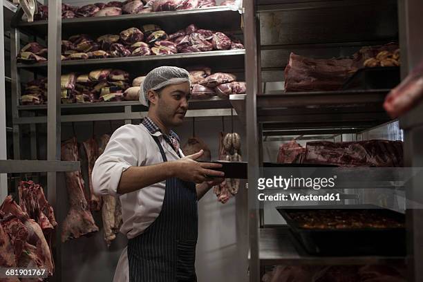 butcher carrying tray in butchery cold store - metzger stock-fotos und bilder