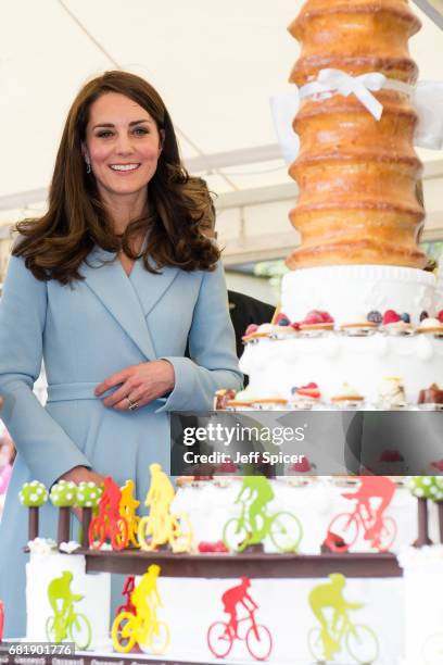 Catherine, Duchess of Cambridge views a cake with a cycling design as she tours a cycling themed festival and unveils a mural of British cyclist Tom...