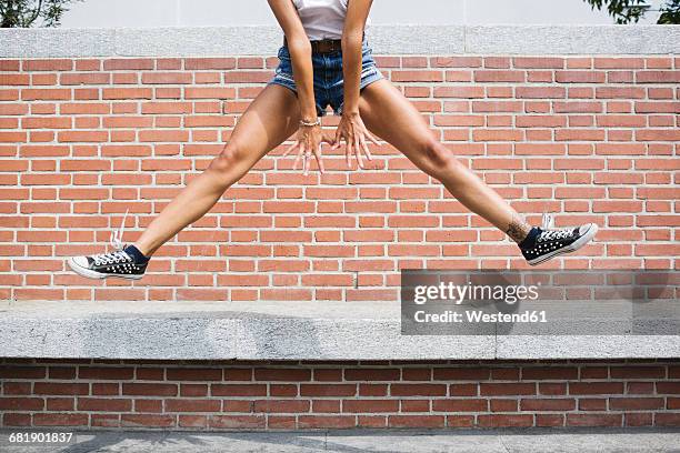 low section of woman in hot pants jumping at brick wall - legs spread woman stock pictures, royalty-free photos & images