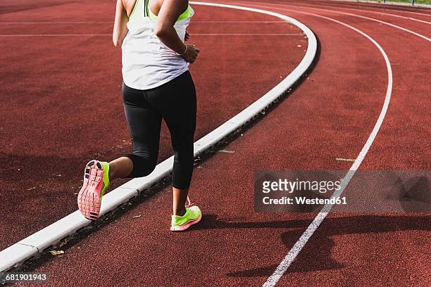young woman running on tartan track - tartanbahn stock-fotos und bilder