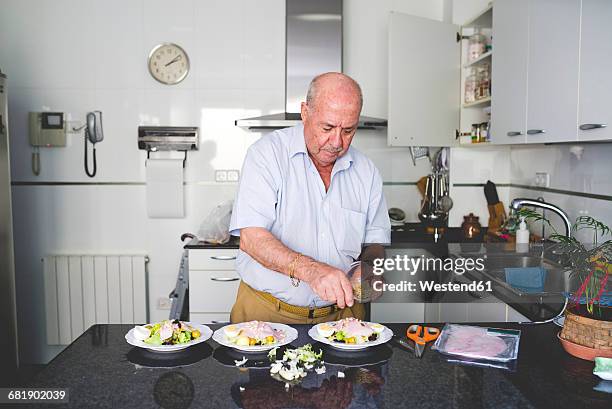 senior man preparing salad in the kitchen - alter mann kocht stock-fotos und bilder