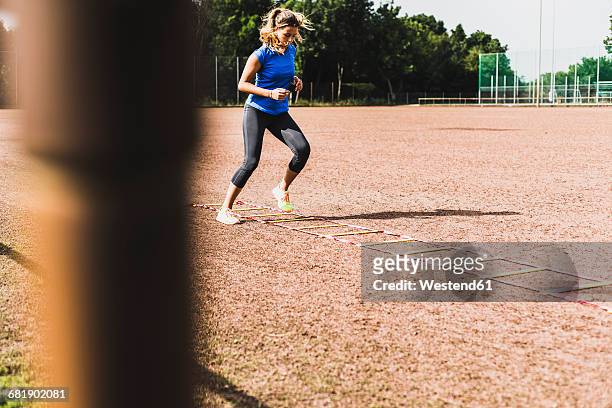 young woman exercising on sports field with agility ladder - agility ladder stock-fotos und bilder