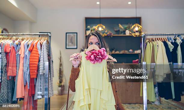 woman holding dress in a boutique - choosing clothes stock pictures, royalty-free photos & images