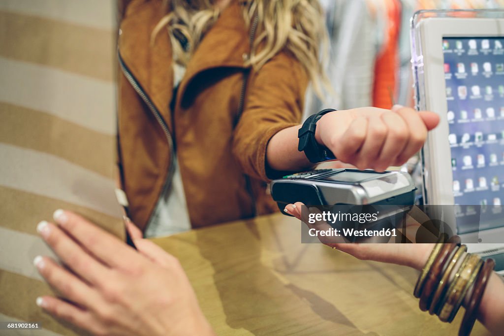Woman paying using smartwatch with NFC technology in a store