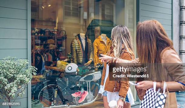 two women looking at shop window of a boutique - store window stock pictures, royalty-free photos & images