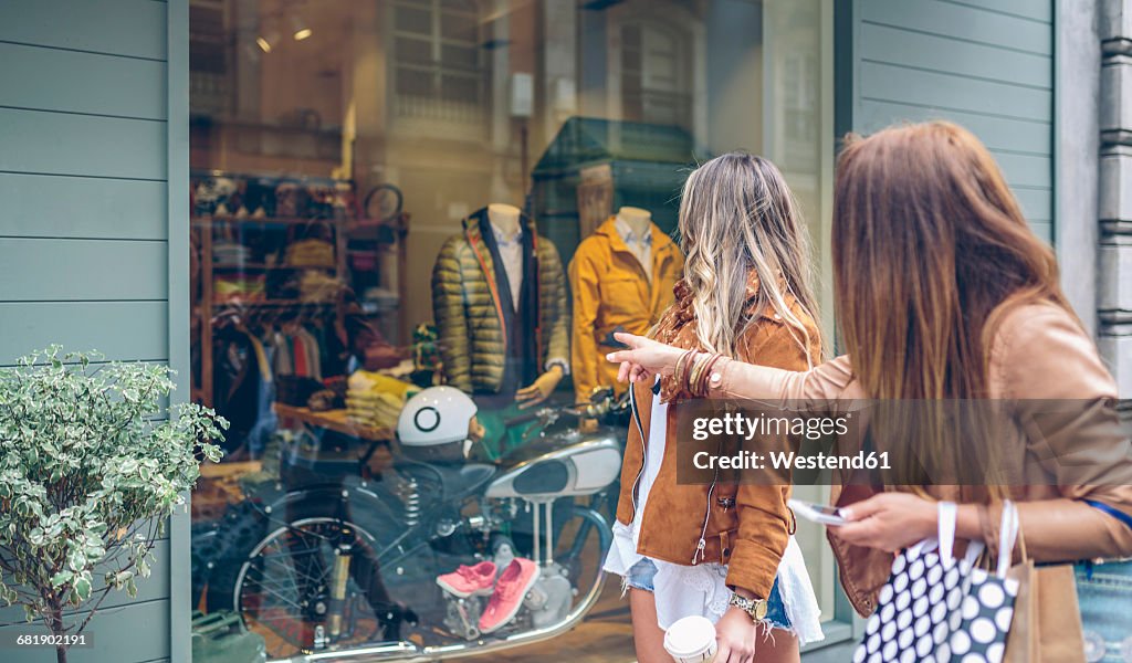 Two women looking at shop window of a boutique