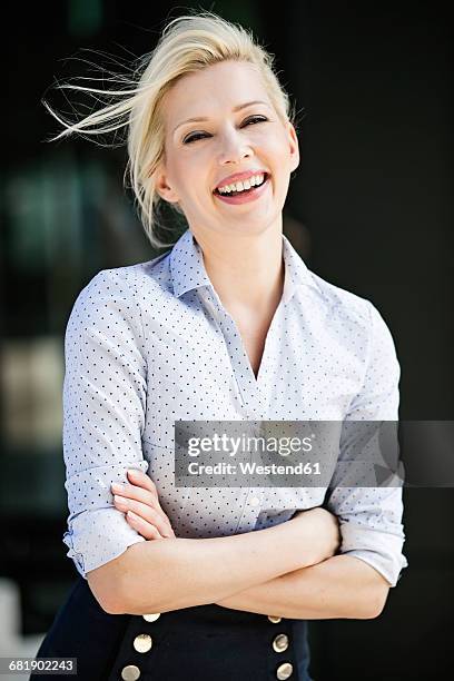 portrait of laughing blond businesswoman with arms crossed - waist up photos stock-fotos und bilder