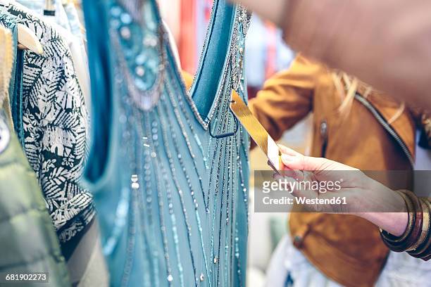 close-up of woman checking price tag of a dress in a boutique - clothing tag stock pictures, royalty-free photos & images