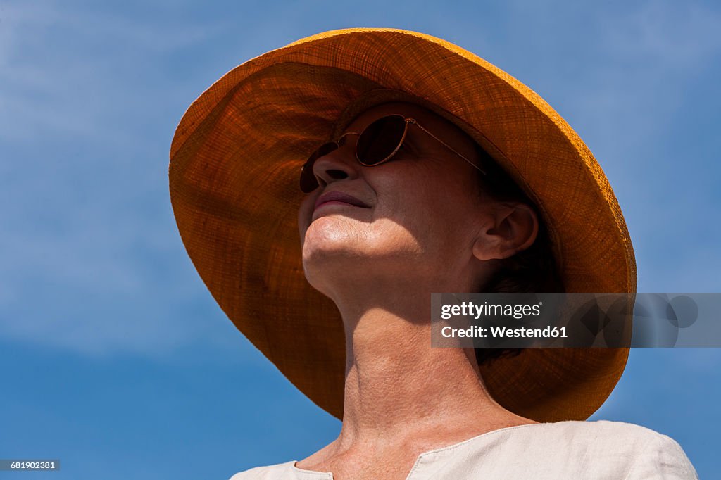 Smiling woman wearing summer hat and sunglasses