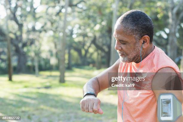 senior black man with headphones and fitness tracker - fitness tracker stock pictures, royalty-free photos & images