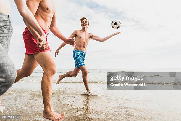 friends running with a ball and tyre on the beach - french football stock-fotos und bilder