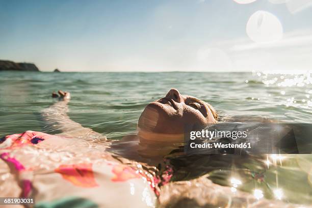 teenage girl floating in the sea - girls on holiday stock-fotos und bilder