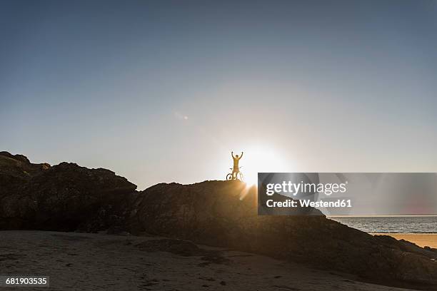 france, crozon peninsula, mountainbiker lifting up his bike at sunset - finistere ストックフォトと画像