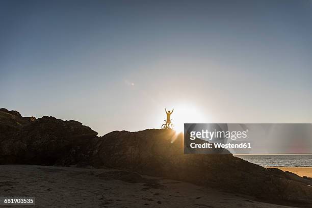 france, crozon peninsula, mountainbiker lifting up his bike at sunset - finistere imagens e fotografias de stock