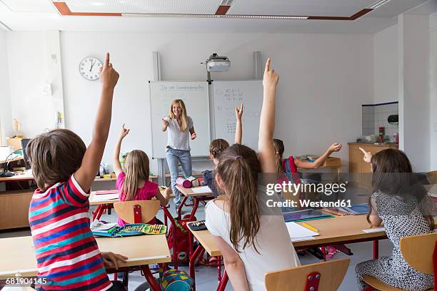 active pupils raising their hands in class - elementary school classroom stock pictures, royalty-free photos & images