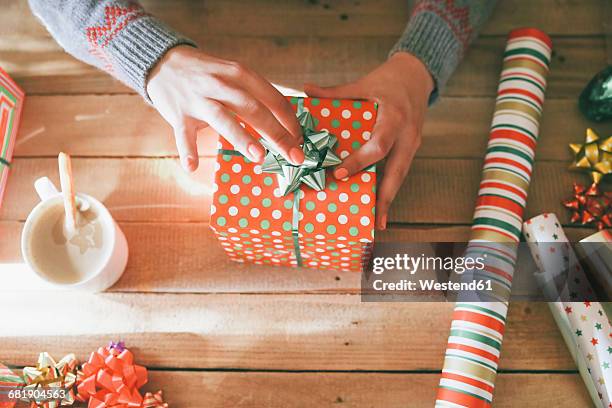 woman's hands placing tie on christmas gift - sala di lusso foto e immagini stock